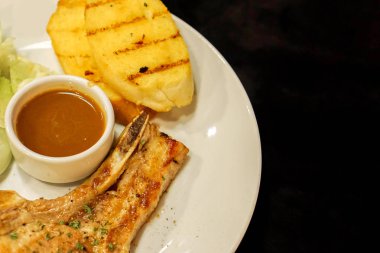 Portre ve t-bone siyah arka plan üzerine beyaz seramik plaka üzerinde biber soslu domuz eti biftek ve sarımsak ekmek izole kırpma.