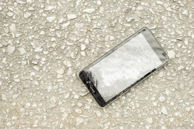 Üstten görünüm siyah cep telefonu kaza geri dönmesine yol ve yol arka plan üzerinde doğal güneş ışığı ile kırık camlar.