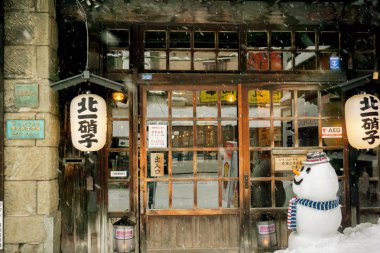 Otaru, Hokkaido, Japonya, 14 Şubat 2018: Ön kış kar yağması, kardan adam bebek ile antik Japon restoranı ve vintage. Otaru kışın aşkın şehri ve çiftlerin hedef seçildi.