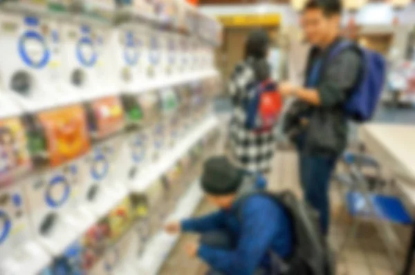 Blurred and out focus of tourists men playing gashapong vending machine in Japan toys shop. Gashapong is one of vending machine dispensed capsule toys,  Popular among tourists visiting Japan.