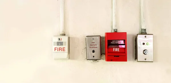 Fire alarm and fire equipment for call to fire station with bright natural sunlight install on office building background.