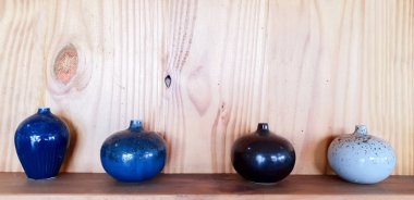 Ahşap raf ve duvar arka plan üzerinde çeşitli seramik vazo ve çiçek pot süslemeleri.