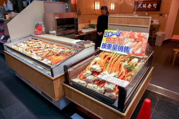 日本大阪 2019年1月16日 在新鲜市场海鲜店门前 一个小海鲜冰柜陈列着大量烧焦的王蟹腿和对虾 上面写着日本五颜六色的招牌和价格标签 — 图库照片
