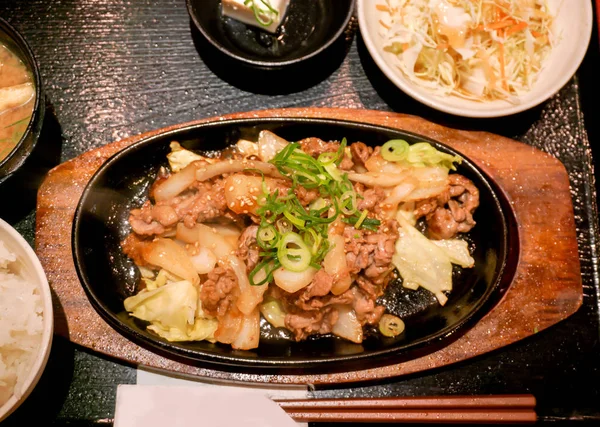日本食品的顶视图 热锅炒猪肉与日式酱 与沙拉在黑色托盘背景 — 图库照片