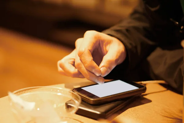 Mano de juego humano y tocar su teléfono móvil en la mesa de madera — Foto de Stock