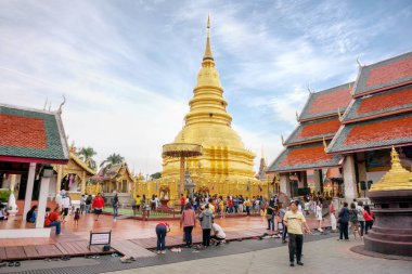 Lamphun, Tayland-31 Aralık 2018 : Wat Phra'daki altın devasa pagoda ve Budist Lanna sanatı tapınağı Parlak mavi gökyüzü ve pamuk üzerinde birçok turistle Hi Li Poon Chai arka plan olabilir.