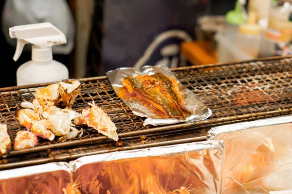 Closeup burned King crab legs and grilled Japanese eels fish on stove to sale for customer at Kuromon market, Osaka, Japan. Burned King crab legs and grilled Japanese eels fish is popular in tourist.