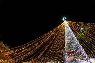 Gece arkaplanındaki Noel ağacı ışıklandırması sahnesi ve metinler için boşluk.