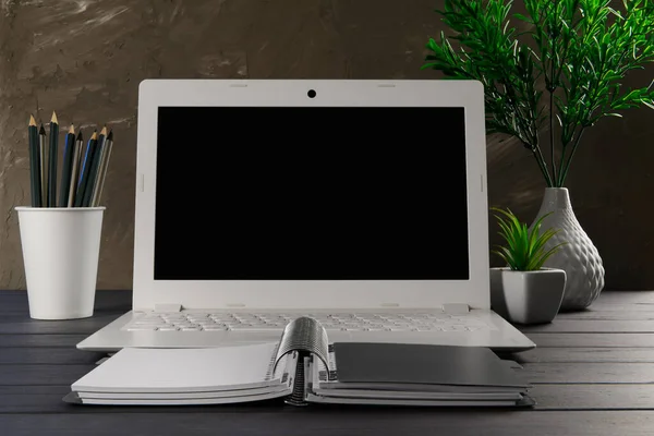 快適な職場のオフィス 空白のノートパソコンとノートブックとワークテーブル ホームオフィス デザイナー快適なワークスペース オフィスの机の電源と暗い背景の花 — ストック写真