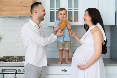 Mutfakta mutlu bir aile, evli, küçük bir çocuğu ve hamile bir kadın var.