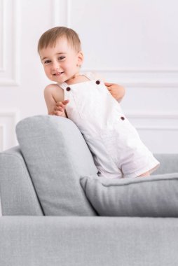 Oturma odasındaki kanepede oynayan gülümseyen bir çocuğun portresi.