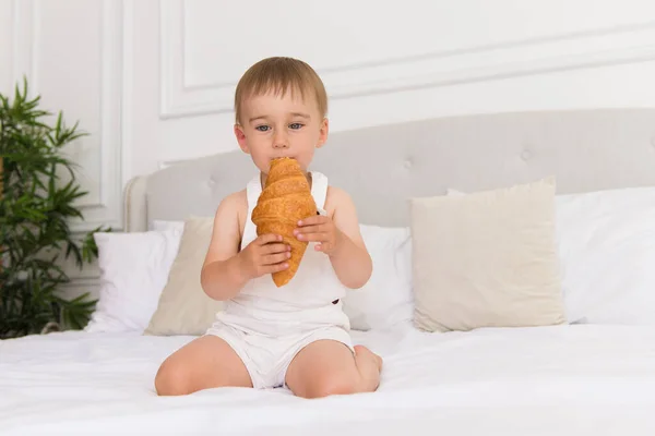 Iloinen Muotokuva Pieni Hymyilevä Poika Lapsi Pelaa Syö Croissant Istuu — kuvapankkivalokuva