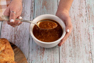 Tahta bir masada beyaz bir kasede soğan çorbası.