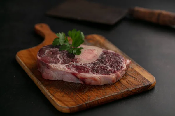 Slice of raw beef shank on a cutting board on a dark background
