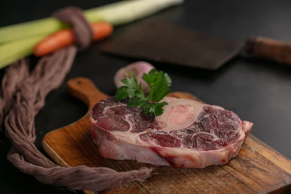 黒地のまな板の上に野菜と生の牛肉のシャンクのスライス — ストック写真