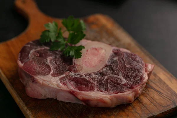 暗い背景にまな板に生の牛肉のシャンクのスライス — ストック写真