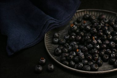 Koyu arkaplanda bir tepside çiğ yaban mersini.