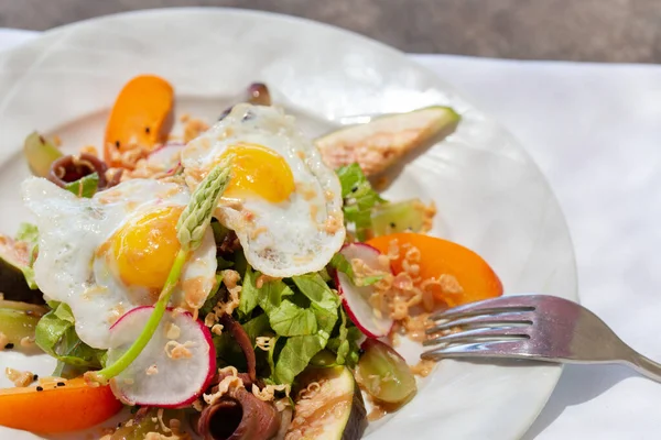 Salad plate with smoked duck breast and fried eggs on the table