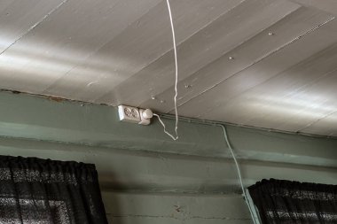 Elektrik prizi bir eski rustik yıpranmış ahşap duvar üzerinde tavanda asılı bir gevşek powercord ile monte edilmiş ve topraklanmış elektrik prizine takın - konsept ev elektrik maliyeti, elektrik güvenliği, verimliliği ve enerji tüketimi.