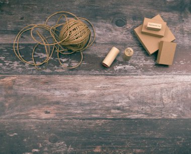 Sanatsal el işi malzemeleri ve kenevir ipliği sanat aletleri, doğal karton kutular ve yaratıcı ev yapımı hediye paketleme ve el sanatları için pullar, kopyalanmış ahşap arka planda.
