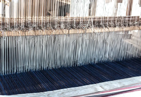 Detail of an old traditional vintage weaving loom with many cotton strings tied to a wooden frame as a professional handwork manufacturing tool for handmade weave production in a textile workshop — Stock Photo, Image