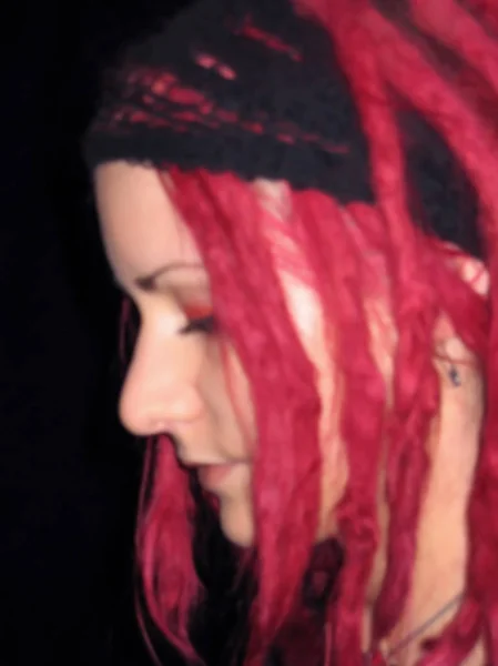Blurred face portrait closeup of young independent caucasian teenager girl looking down with colourful unusual vibrant red dyed dreadlocks hair - Concept of punk rock youth culture, freak