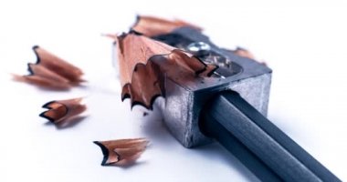 Beyaz arka planda ahşap girdap talaşı olan gri metal kalemtraşlı bir kalemle kalem açmanın makro yakın plan çekimi - okul eğitimi kavramı, öğrenme, öğrenme, öğrenme, ödev veya yazar