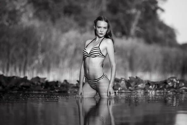 Young woman wearing striped bikini at a lake