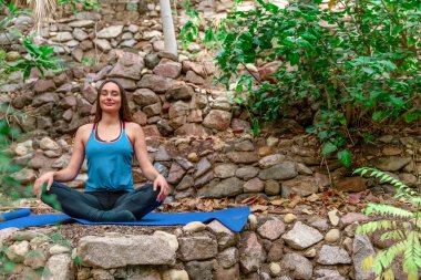 Genç bir kadın parkta yoga yapıyor ve eğitiyor. Açık hava kadınlarının sporu