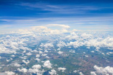Beyaz bulutların üzerindeki güzel mavi gökyüzü manzarası ve uçak penceresinden kara manzarası