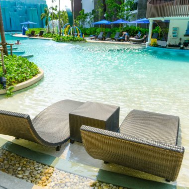 Plaj sandalyeleri ve tropikal otel otelinde lüks yüzme havuzunda bar tezgahı, dinlenme ve havuzda boş zaman..