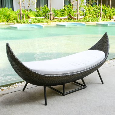 Tropikal oteldeki havuz kenarında dinlenen rattan kanepesi..