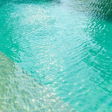 Parlak mavi yüzme havuzunun önündeki taştan sınıra yakın. Güneş ışığı yansımalı havuzların dekorasyonu ve tasarımı, tatil, rahatlama, kaçış gözlemi