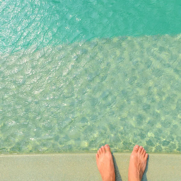 男子赤脚站在明亮的蓝色游泳池边 水有阳光映照 出游的概念 — 图库照片