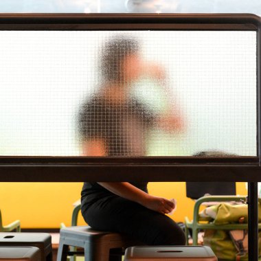 Kadın modern kahve dükkanında otururken kahve içiyor. Ayna bölümünden bak (siluet)