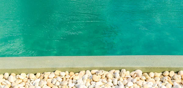 在明亮的蓝色游泳池前 用石头围起来 用阳光反射 出游等方式装饰和设计游泳池 — 图库照片