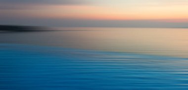 Sudaki kırılma arkaplanı bulanık. Sonsuzluk Yüzme Havuzu 'nun panoramik dramatik manzarası alacakaranlık zamanlarında denizde gün batımıyla