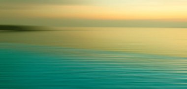 Sudaki kırılma arkaplanı bulanık. Sonsuzluk Yüzme Havuzu 'nun panoramik dramatik manzarası alacakaranlık zamanlarında denizde gün batımıyla