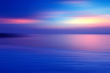 Hareket, suda kırılma arkaplanı bulanıklaştırmış. Alacakaranlık zamanlarında denizde sonsuzluk günbatımının panoramik dramatik görüntüsü