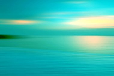 Hareket, suda kırılma arkaplanı bulanıklaştırmış. Alacakaranlık zamanlarında denizde sonsuzluk günbatımının panoramik dramatik görüntüsü