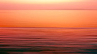 Hareket, suda kırılma arkaplanı bulanıklaştırmış. Alacakaranlık zamanlarında denizde sonsuzluk günbatımının panoramik dramatik görüntüsü