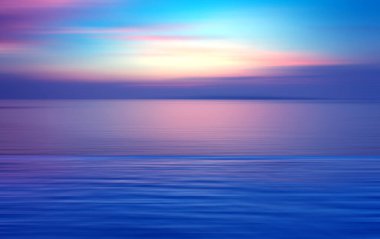 Hareket, suda kırılma arkaplanı bulanıklaştırmış. Alacakaranlık zamanlarında denizde sonsuzluk günbatımının panoramik dramatik görüntüsü