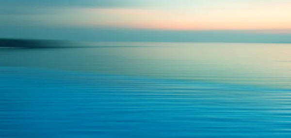 Sudaki kırılma arkaplanı bulanık. Sonsuzluk Yüzme Havuzu 'nun panoramik dramatik manzarası alacakaranlık zamanlarında denizde gün batımıyla