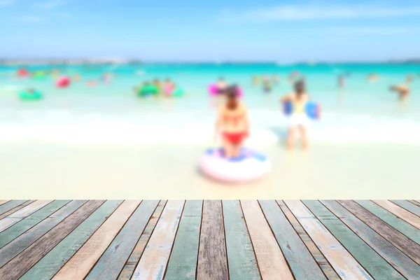 海滩上有模糊的人的木制桌面上 暑假背景的概念 可以用来展示或蒙太奇你的产品 — 图库照片