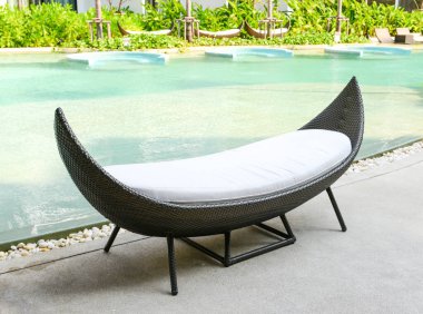 Tropikal oteldeki havuz kenarında dinlenen rattan kanepesi..