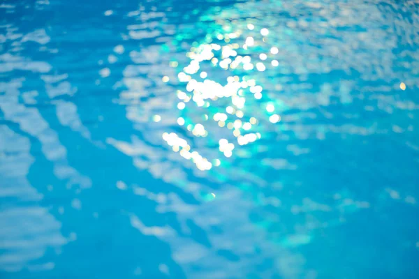 プール内の波打つ青い水の背景の上に柔らかい焦点ボケ光効果 — ストック写真