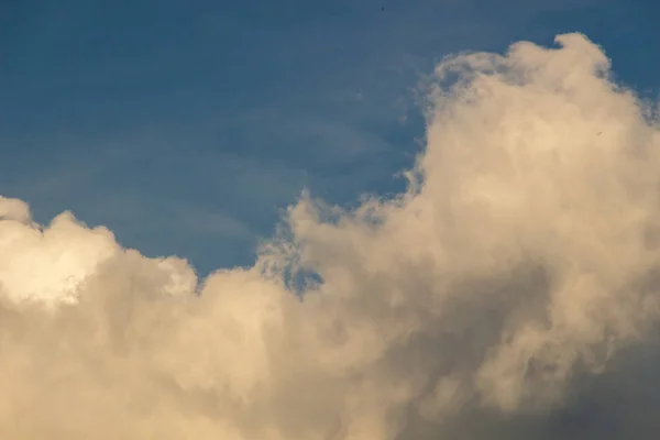 Ljusa soliga moln mot middagstid blå himmel — Stockfoto