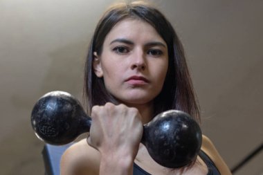 Kız spor salonunda dambıllarla meşgul.