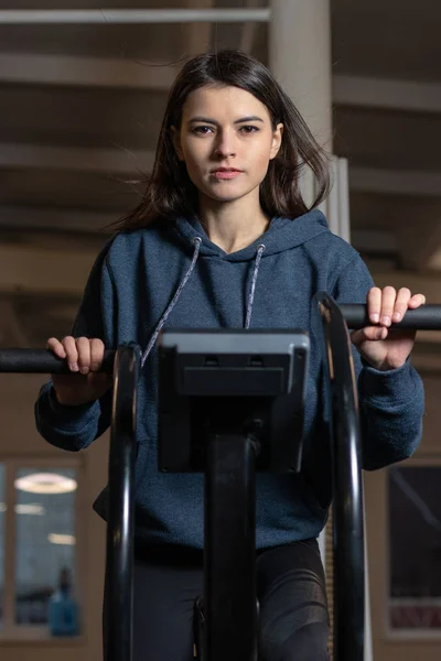Flickan är engagerad på en CrossFit motionscykel i gymmet — Stockfoto