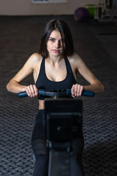 Flickan är engagerad i en rodd Simulator i gymmet — Stockfoto